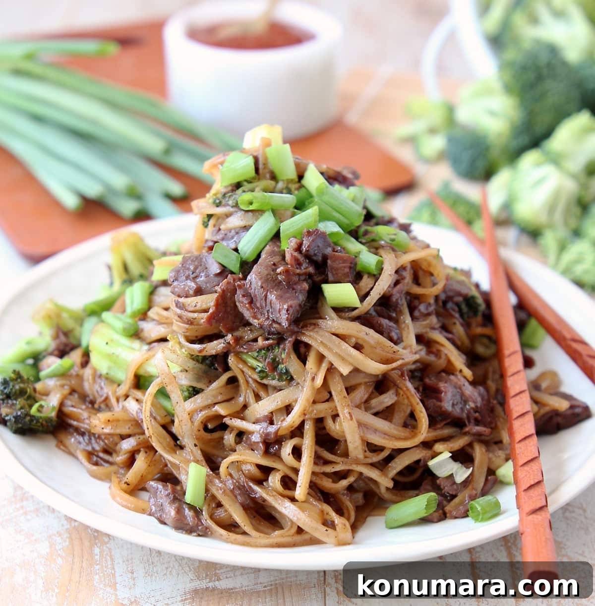 Slow Cooker Black Pepper Beef with Broccoli Recipe 5 Black Pepper Beef and Brocolli with Rice Noodles and Scallions on plate with wood chopsticks