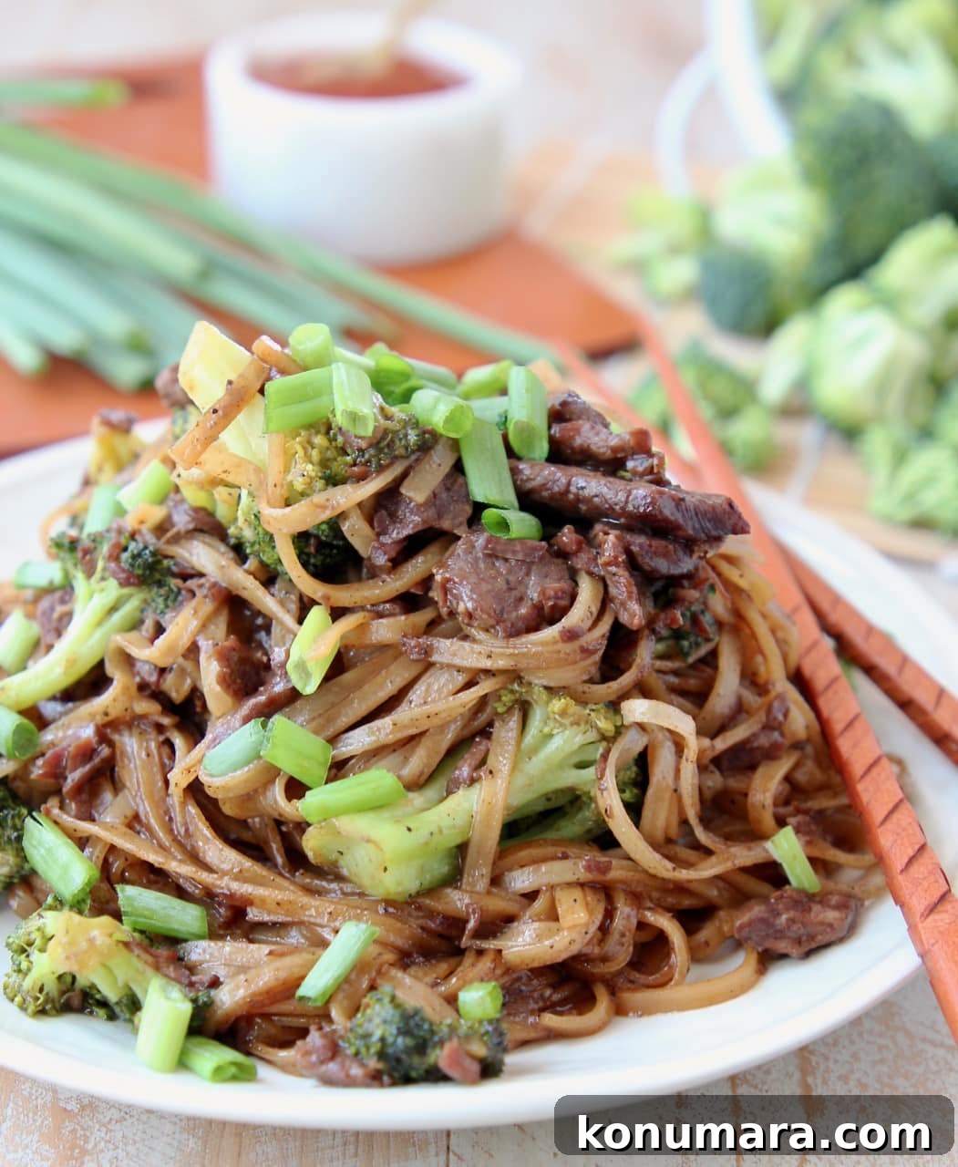 Slow Cooker Black Pepper Beef with Broccoli Recipe 6 Black pepper beef and rice noodles with scallions on plate with wood chopsticks