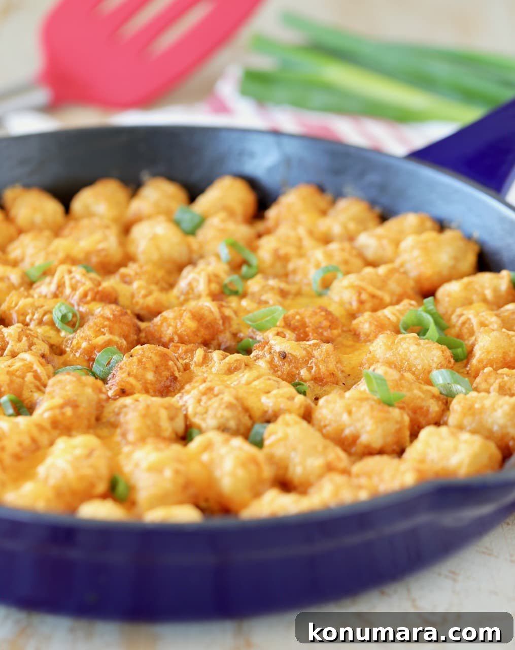 Buffalo Cheeseburger Tater Tot Casserole Recipe 4 Tater Tot casserole with diced green onions in blue cast iron skillet with red spatula