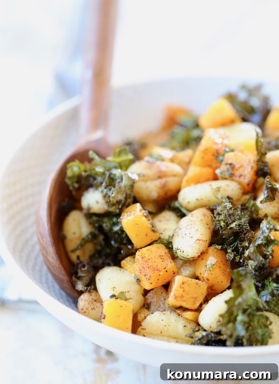 Gnocchi, butternut squash and kale in bowl with wooden spoons