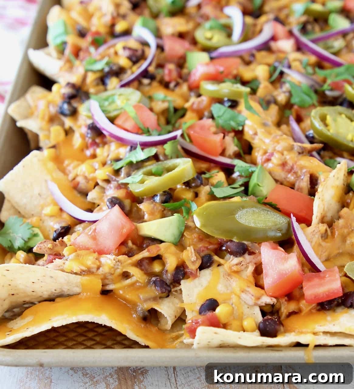 Cheesy Crock Pot Chicken Nachos Recipe 3 Sheet pan of chicken nachos with black beans, cheese, tomatoes, sliced jalapenos, red onions and avocado