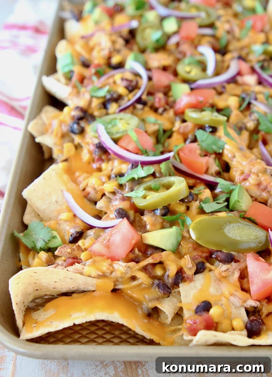 Cheesy Crock Pot Chicken Nachos Recipe 5 Chicken nachos on sheet pan with melted cheese, sliced nacho jalapenos, diced tomatoes and sliced red onions