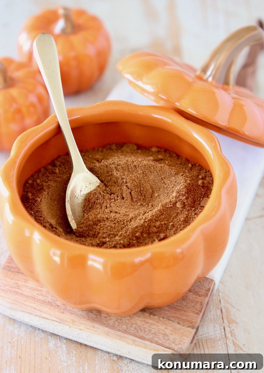 How to Make Pumpkin Pie Spice Blend 5 Homemade pumpkin pie spice in small orange pumpkin bowl with small gold spoon on marble cutting board