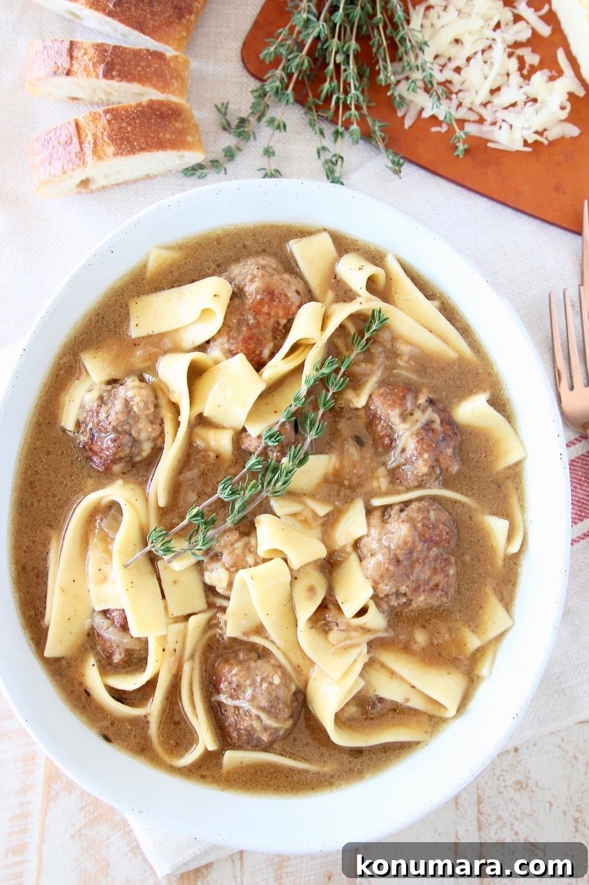 Slow Cooker French Onion Soup with Meatballs 4 Meatball Soup with egg noodles in bowl with springs of fresh thyme, next to a sliced baguette and shredded gruyere cheese