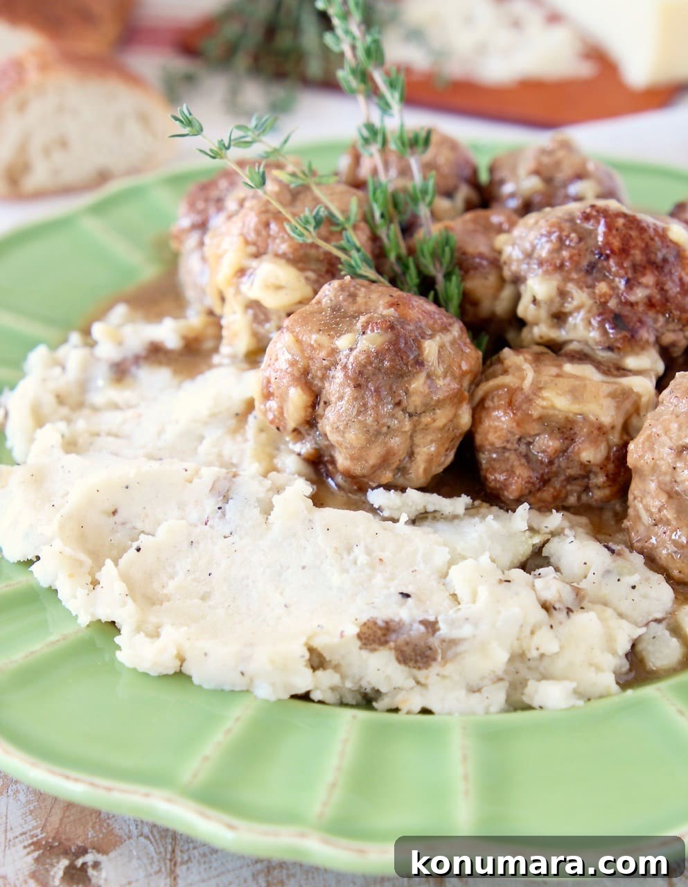 Slow Cooker French Onion Soup with Meatballs 5 Green plate with mashed potatoes and meatballs, a fresh sprig of thyme and sliced baguette in the background