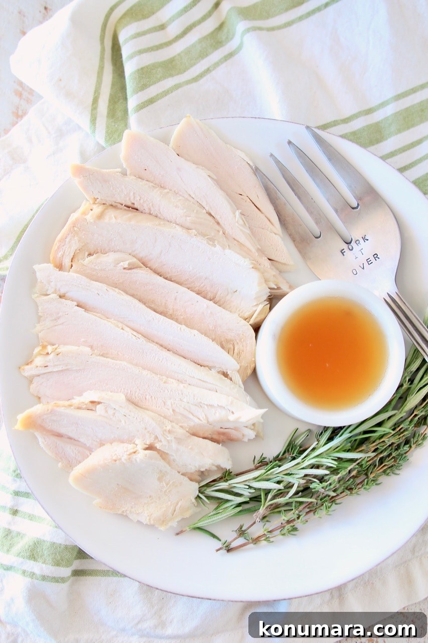 Sliced turkey breast on plate with small white bowl of apple reduction, large fork and fresh rosemary and thyme sprigs, on white and green cloth towel