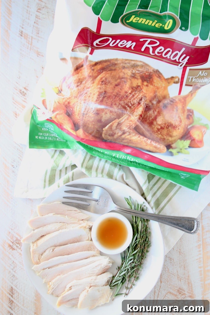 Plate of sliced roasted turkey with large fork, bowl of maple apple reduction and fresh rosemary springs, next to Jennie O Whole Oven Ready Turkey in bag