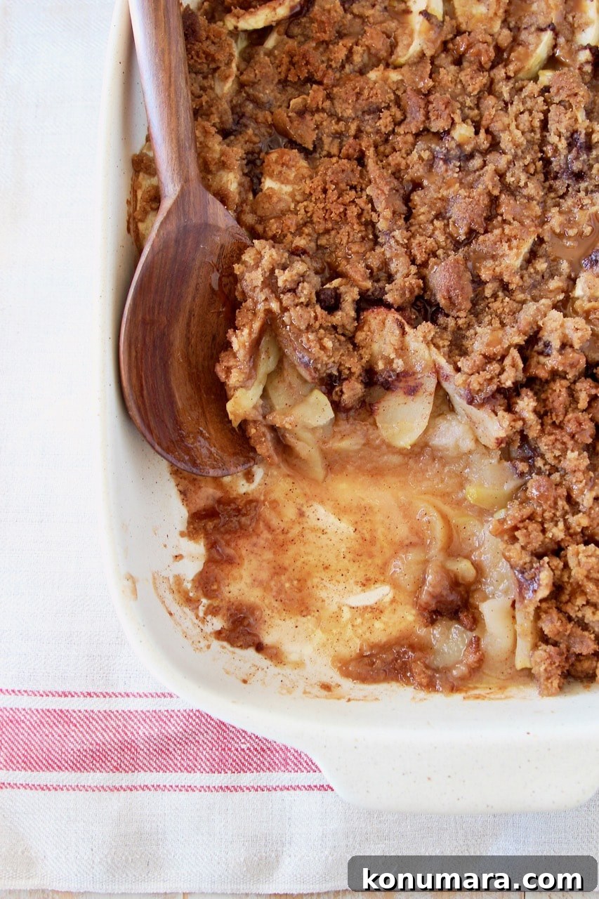 Pumpkin crumble in baking dish with spoonful taken out with wooden spoon in the dish on white and red towel
