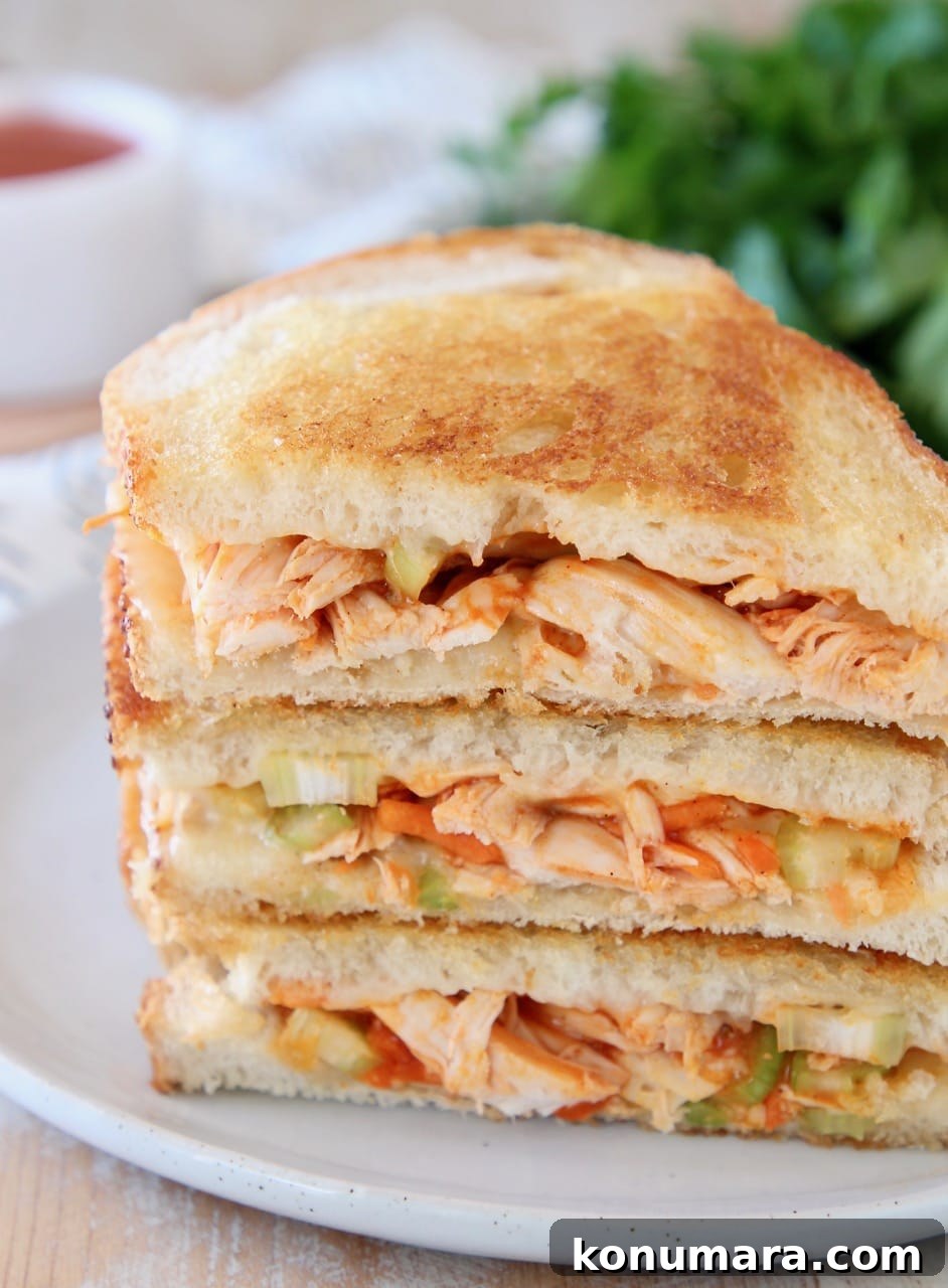 Crispy Buffalo Turkey Grilled Cheese Recipe 4 Buffalo turkey grilled cheese sandwiches, sliced in half diagonally, stacked up on white plate with fresh parsley in the background
