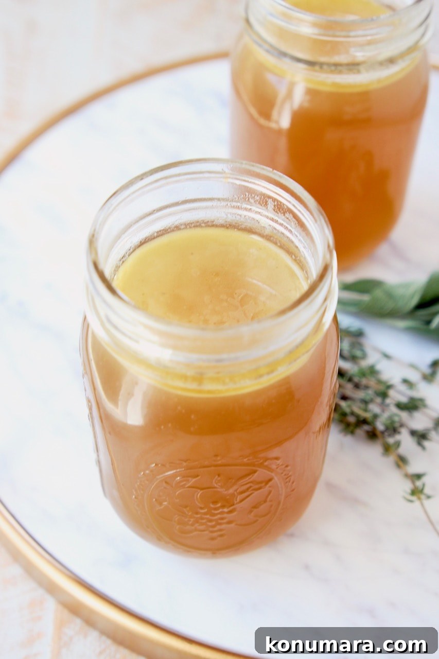 Instant pot turkey stock in mason jars on marble tray with fresh thyme and sage leaves