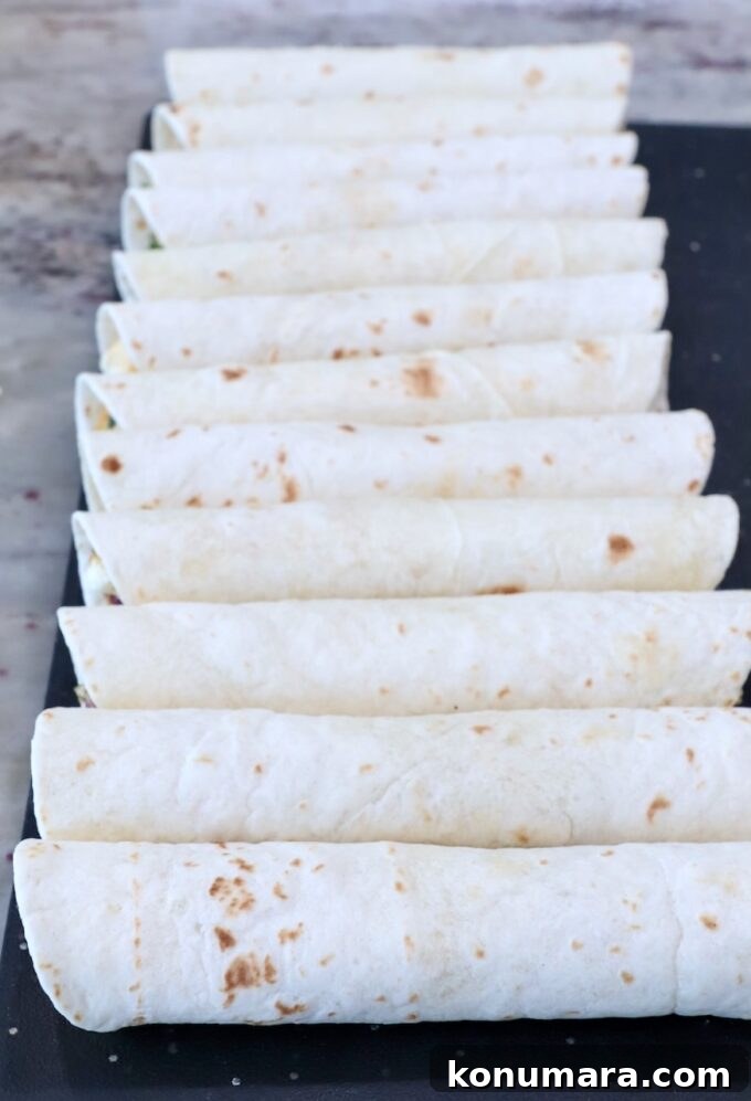 uncooked rolled-up taquitos on a cutting board