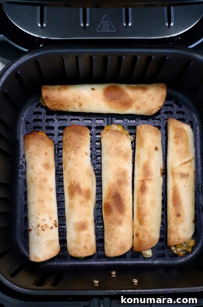 cooked taquitos in an air fryer basket