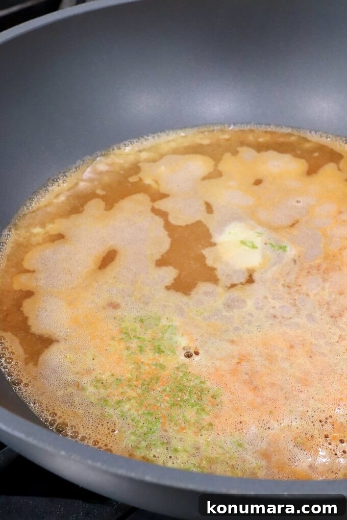 simmering broth in a large pot with lime zest, garlic and ginger