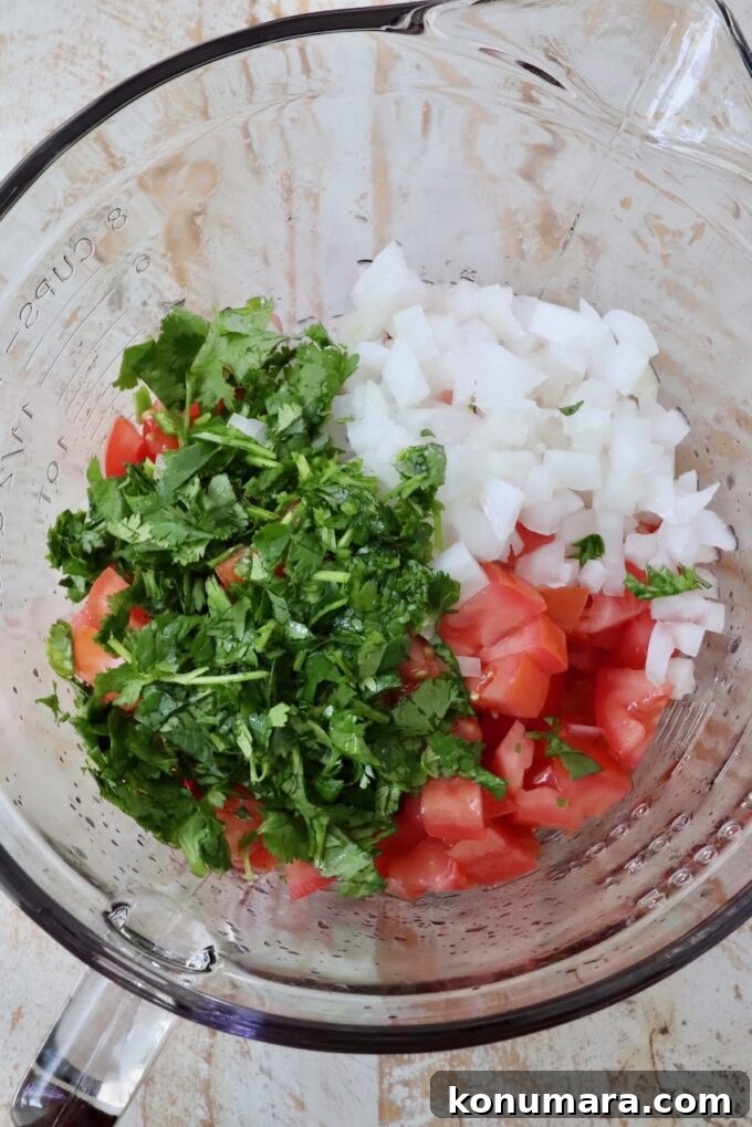 diced tomatoes and onions with fresh cilantro in a glass bowl