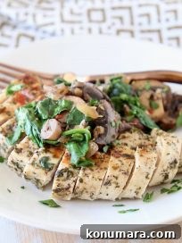 Sliced mushroom spinach chicken breast on plate with copper fork, sitting on gold and white patterned napkin