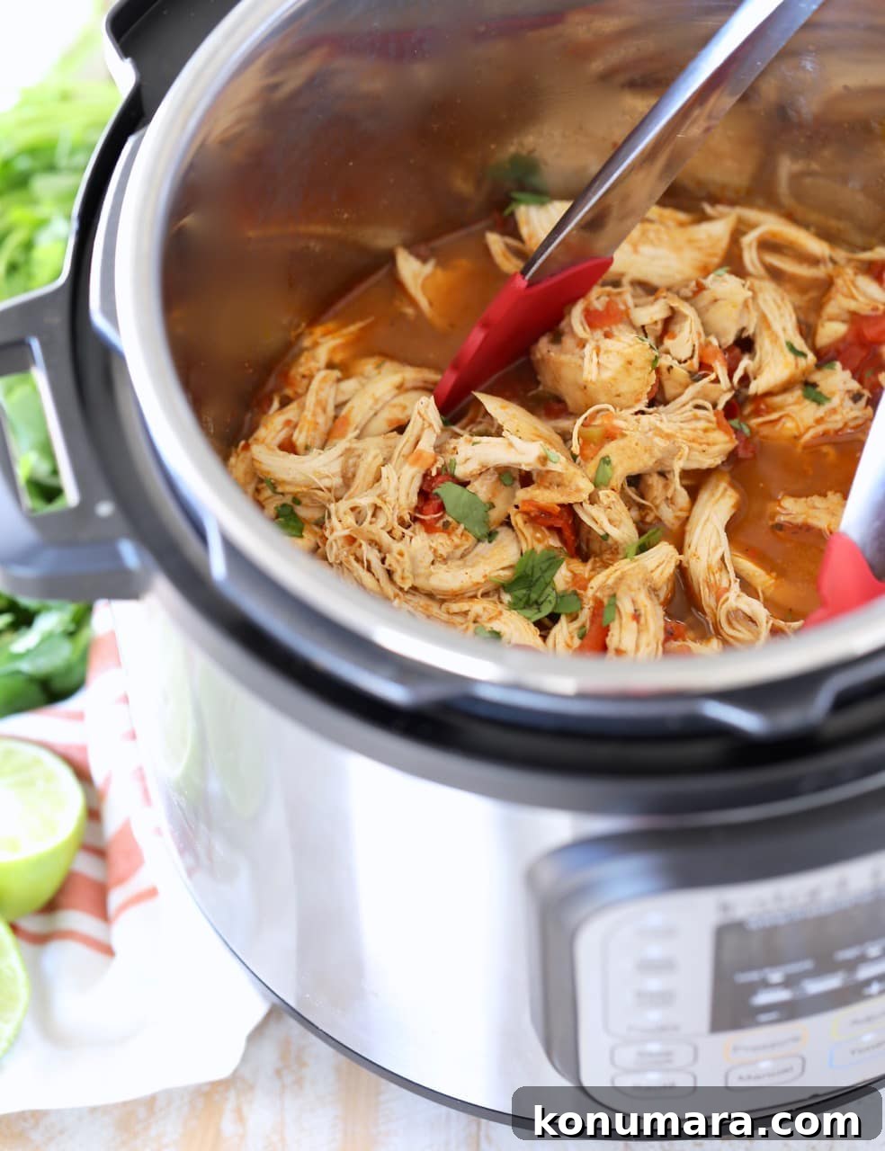 Instant Pot Shredded Chicken Tacos 4 Shredded taco chicken in Instant Pot with red tongs and cilantro