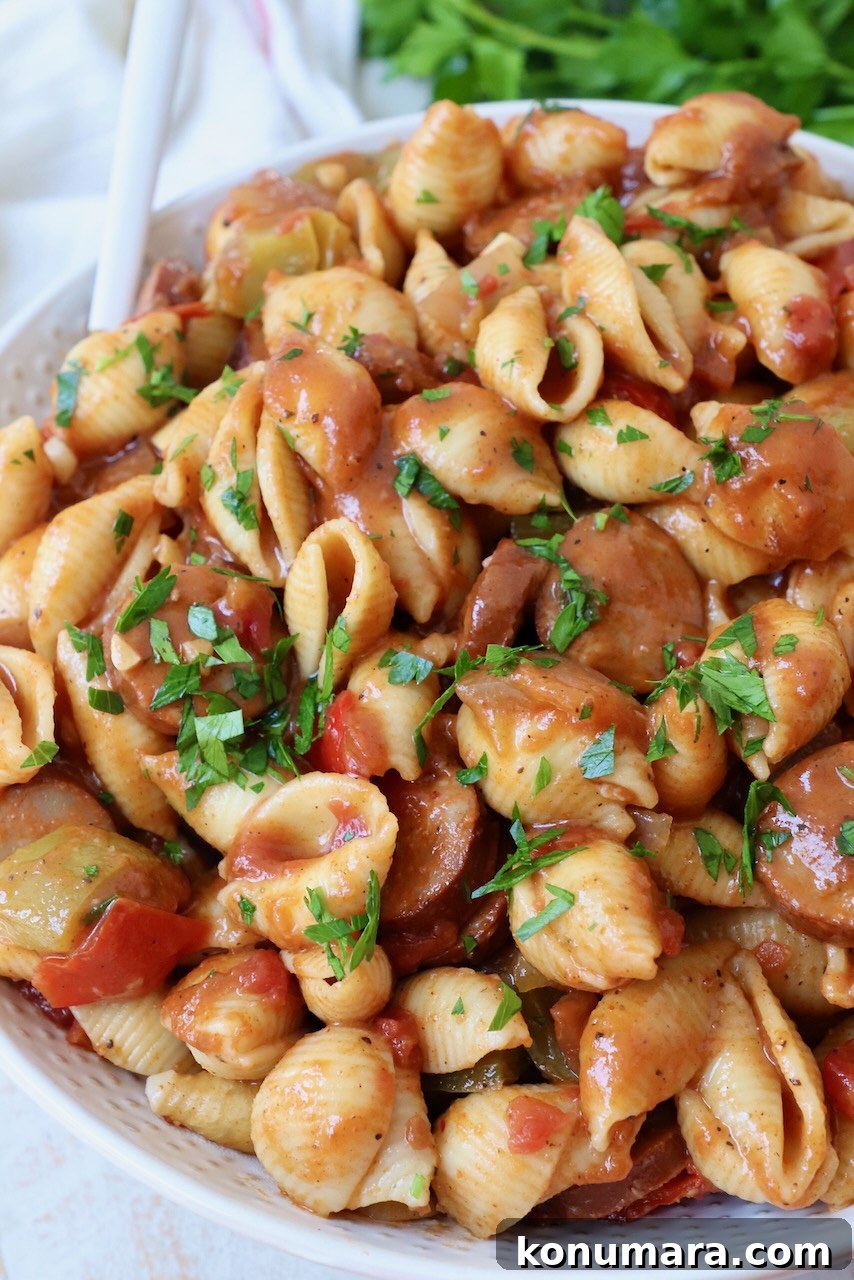 cooked pasta with sausage and bell peppers in a large white bowl