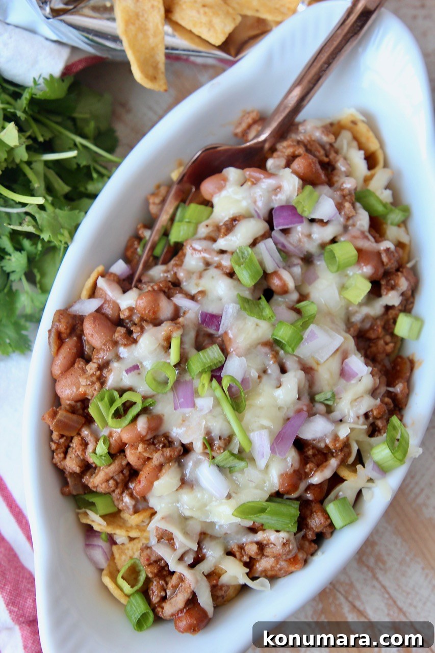 Classic Frito Chili Pie Recipe with Cheesy Corn Chip Topping 5 frito chili pie in white oval bowl topped with diced green onions