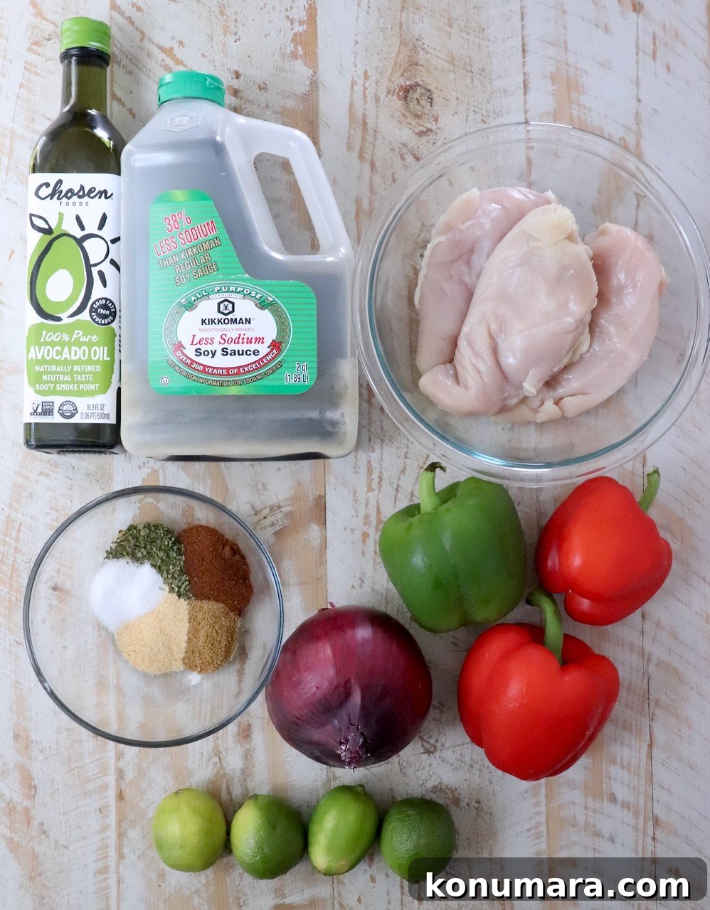 ingredients for chipotle lime marinated chicken fajitas on a white wood board
