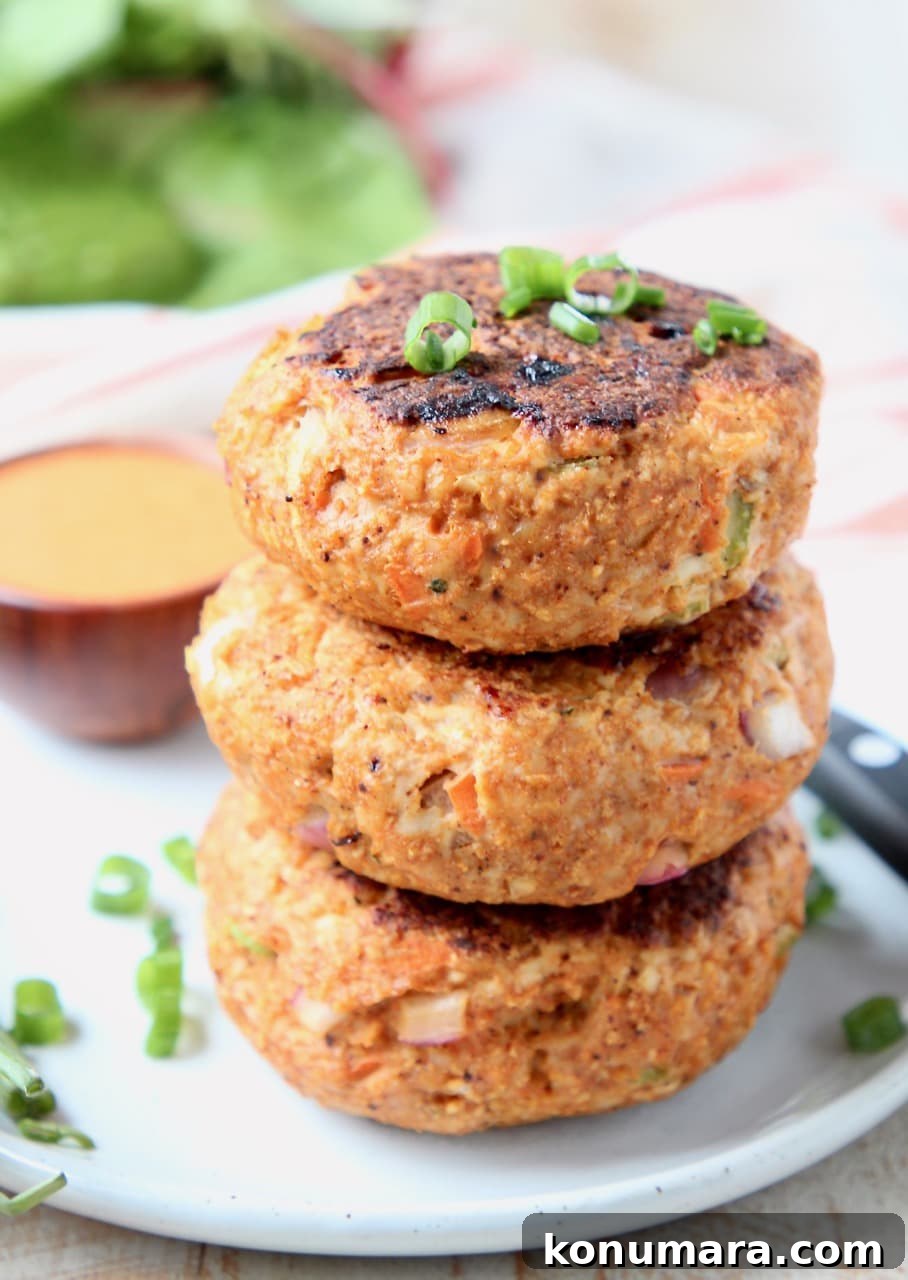 Spicy Buffalo Chicken Burgers with Blue Cheese Slaw 4 Buffalo chicken burger patties stacked on top of each other on white plate