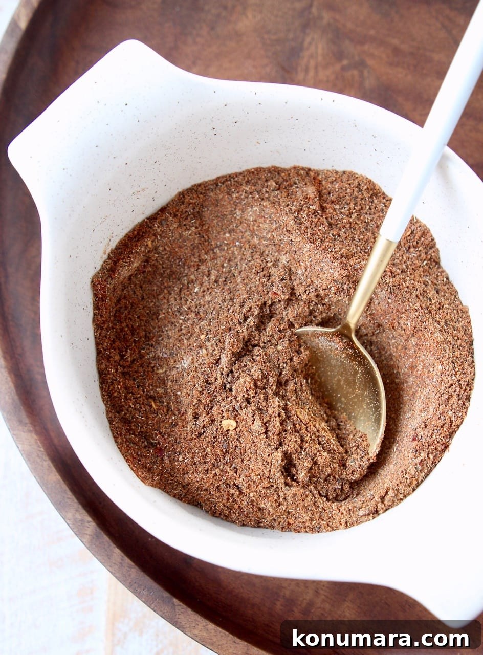 Chili seasoning blend in a white bowl with a gold and white spoon in the bowl