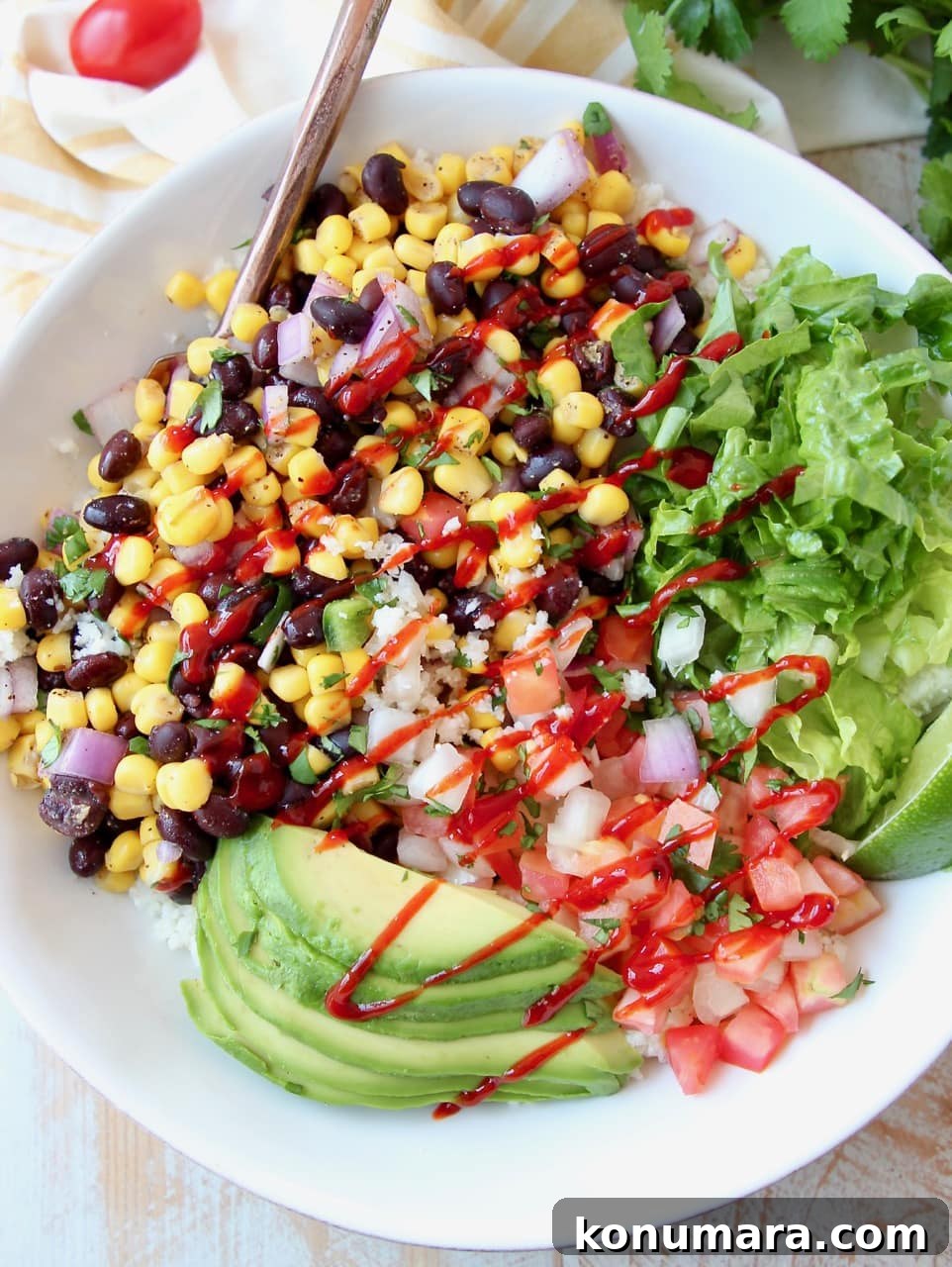Loaded Vegan Burrito Bowl with Black Beans and Avocado 4 Burrito bowl with avocado, corn, tomatoes and black beans, topped with a drizzle of hot sauce in a white bowl