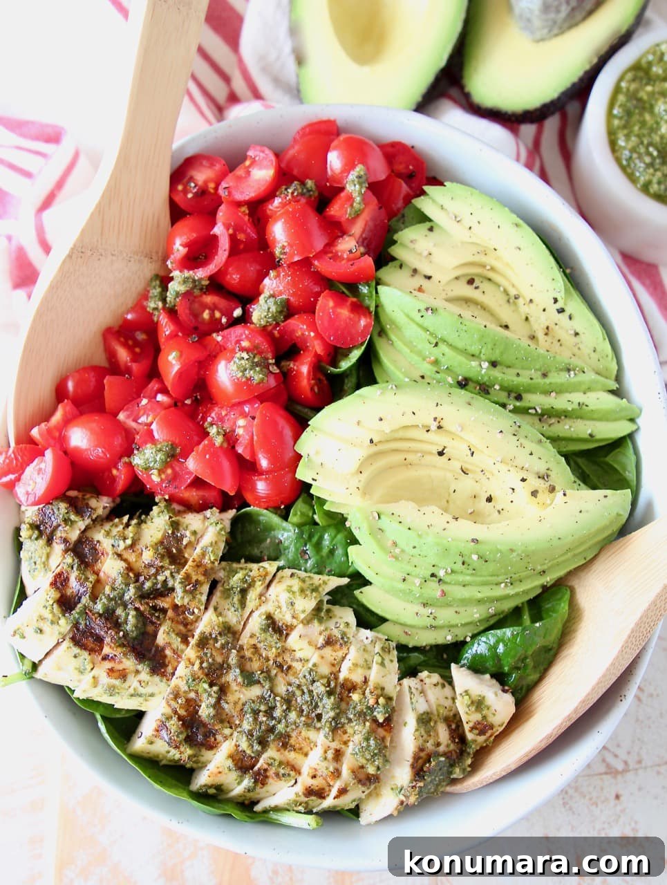 Grilled Chicken and Avocado Pesto Salad 4 Sliced pesto chicken, sliced avocado, diced tomatoes and spinach in large bowl with wooden serving spoons