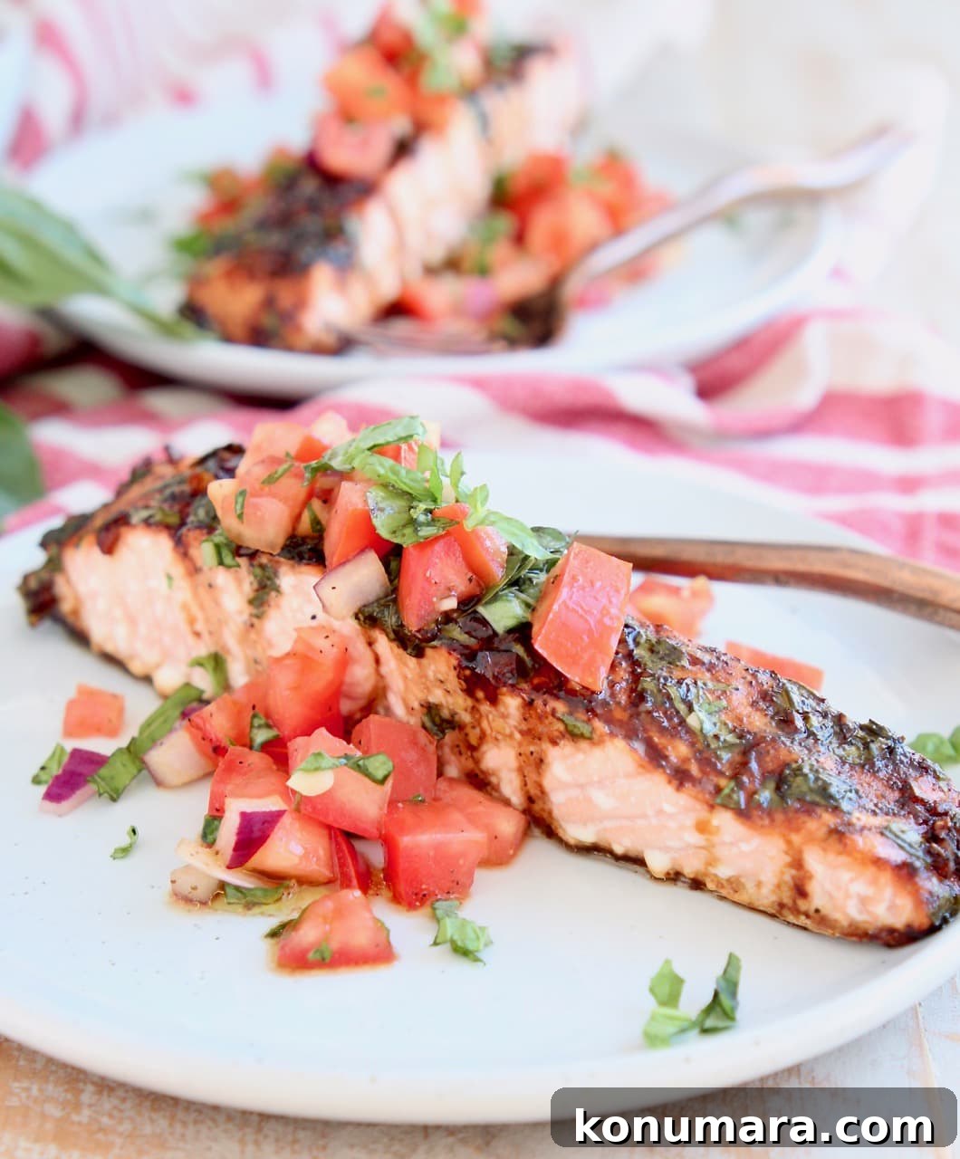 Grilled Salmon with Tomato Bruschetta 4 Piece of baked salmon on a white plate topped with tomato basil bruschetta