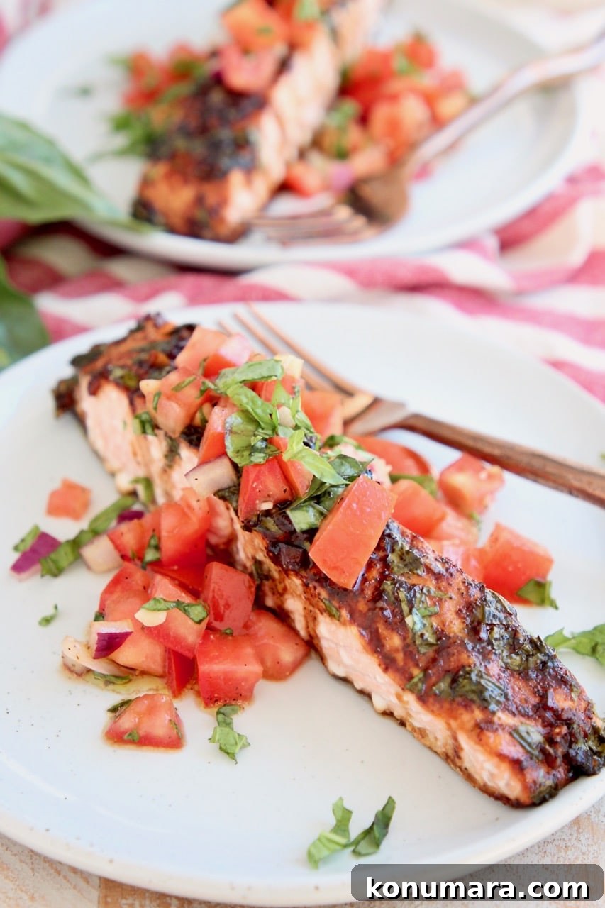Grilled Salmon with Tomato Bruschetta 5 Balsamic glazed piece of salmon on plate topped with tomato basil bruschetta