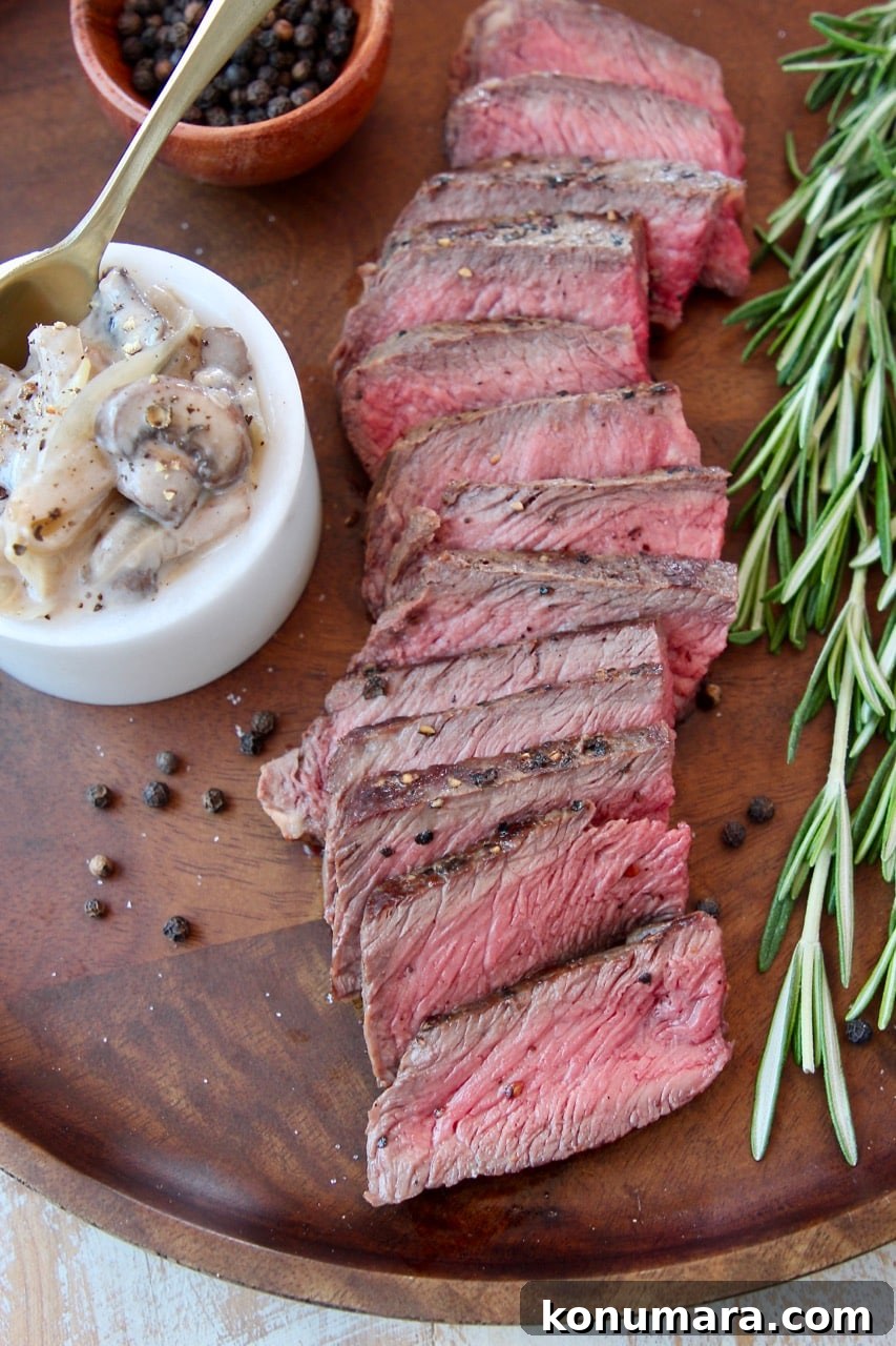 Seared Wagyu Steak with Creamy French Onion Mushrooms 2 Overhead shot of sliced wagyu steak on wood cutting board with rosemary sprigs on the side