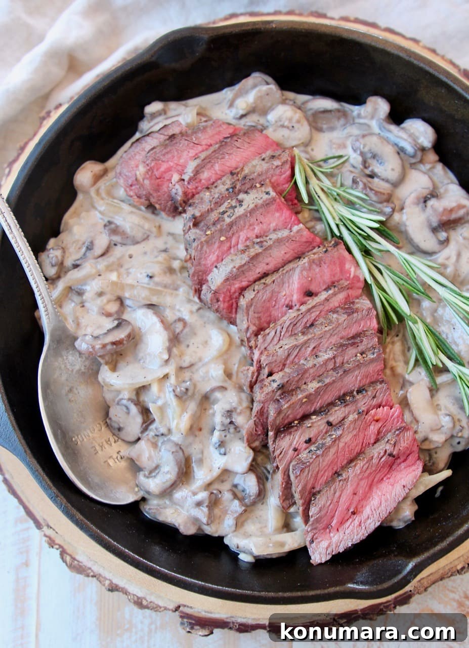 Seared Wagyu Steak with Creamy French Onion Mushrooms 3 Overhead shot of sliced wagyu steak in cast iron skillet with creamy mushrooms and rosemary sprigs