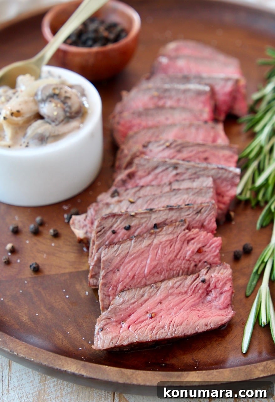 Seared Wagyu Steak with Creamy French Onion Mushrooms 4 Sliced wagyu steak on wood cutting board with fresh rosemary sprigs