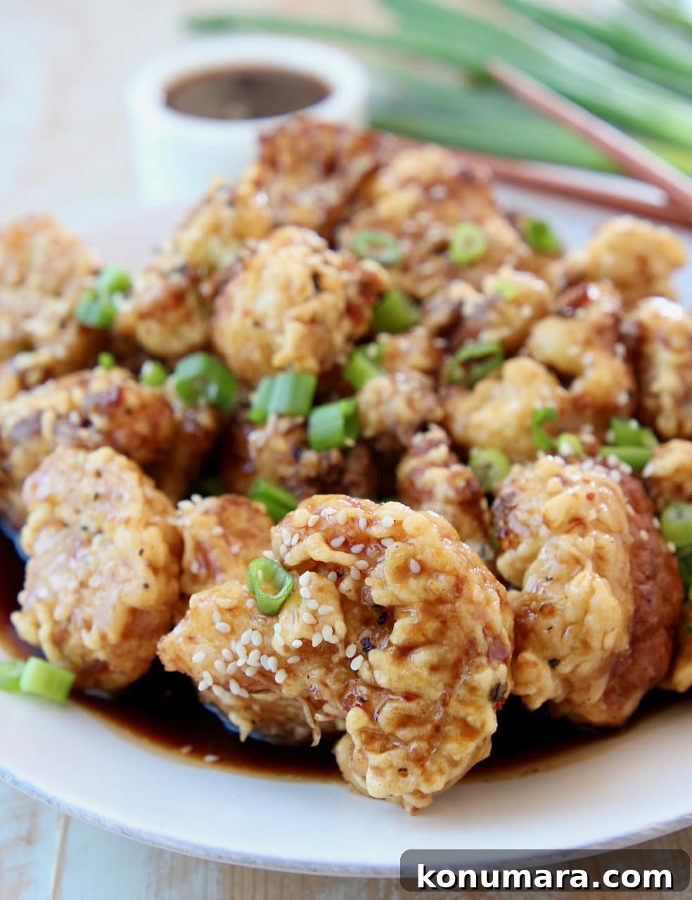 Crispy Korean-Style Fried Cauliflower with Gochujang Glaze 5 Fried Cauliflower in Korean BBQ Sauce on plate topped with diced green onions