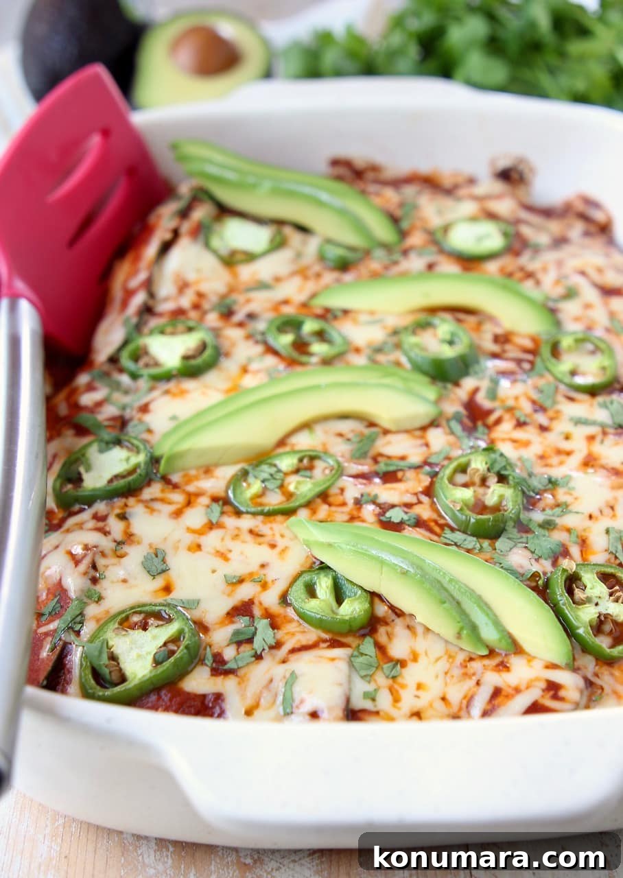 Enchiladas in baking dish with red spatula on the side of the dish
