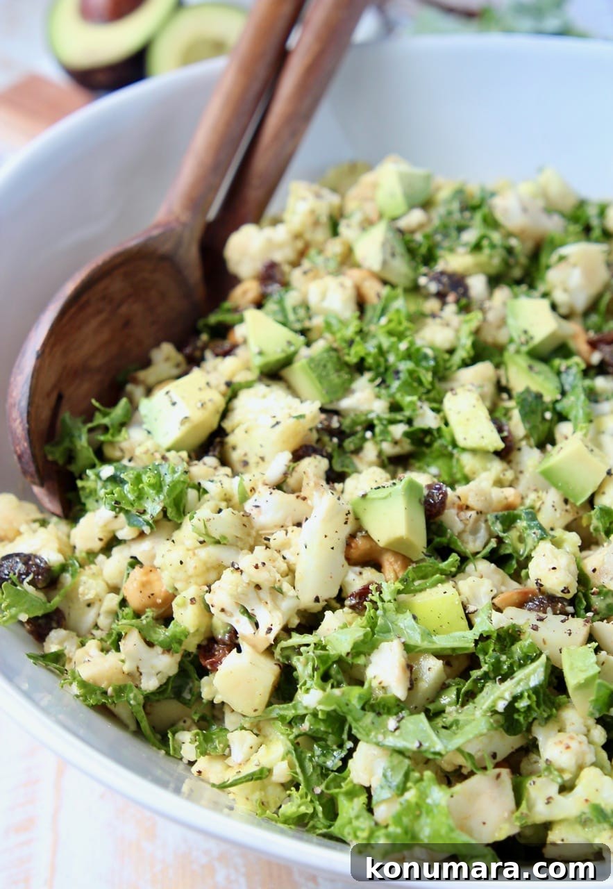 Roasted Cauliflower Salad with Lemon Tahini Dressing 4 Diced cauliflower, kale, avocado and apples in large white bowl with wood serving spoons