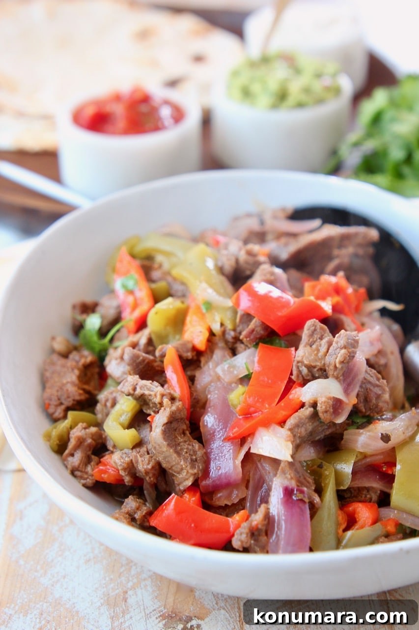 Steak fajitas in white bowl with large spoon
