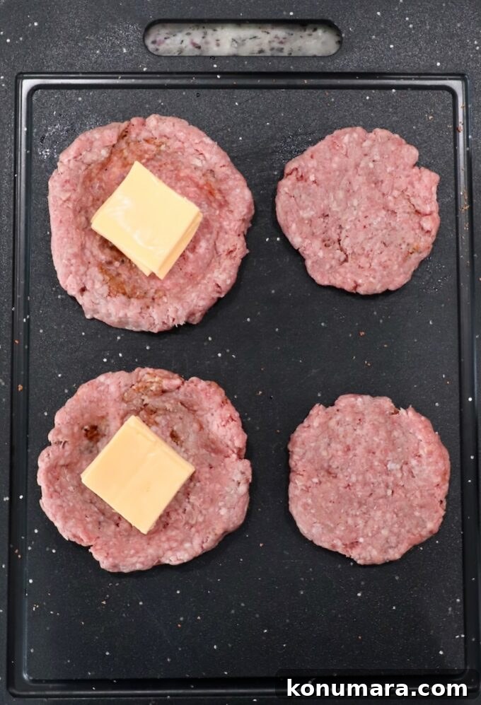 ground beef patties stuffed with cheese slices on a cutting board