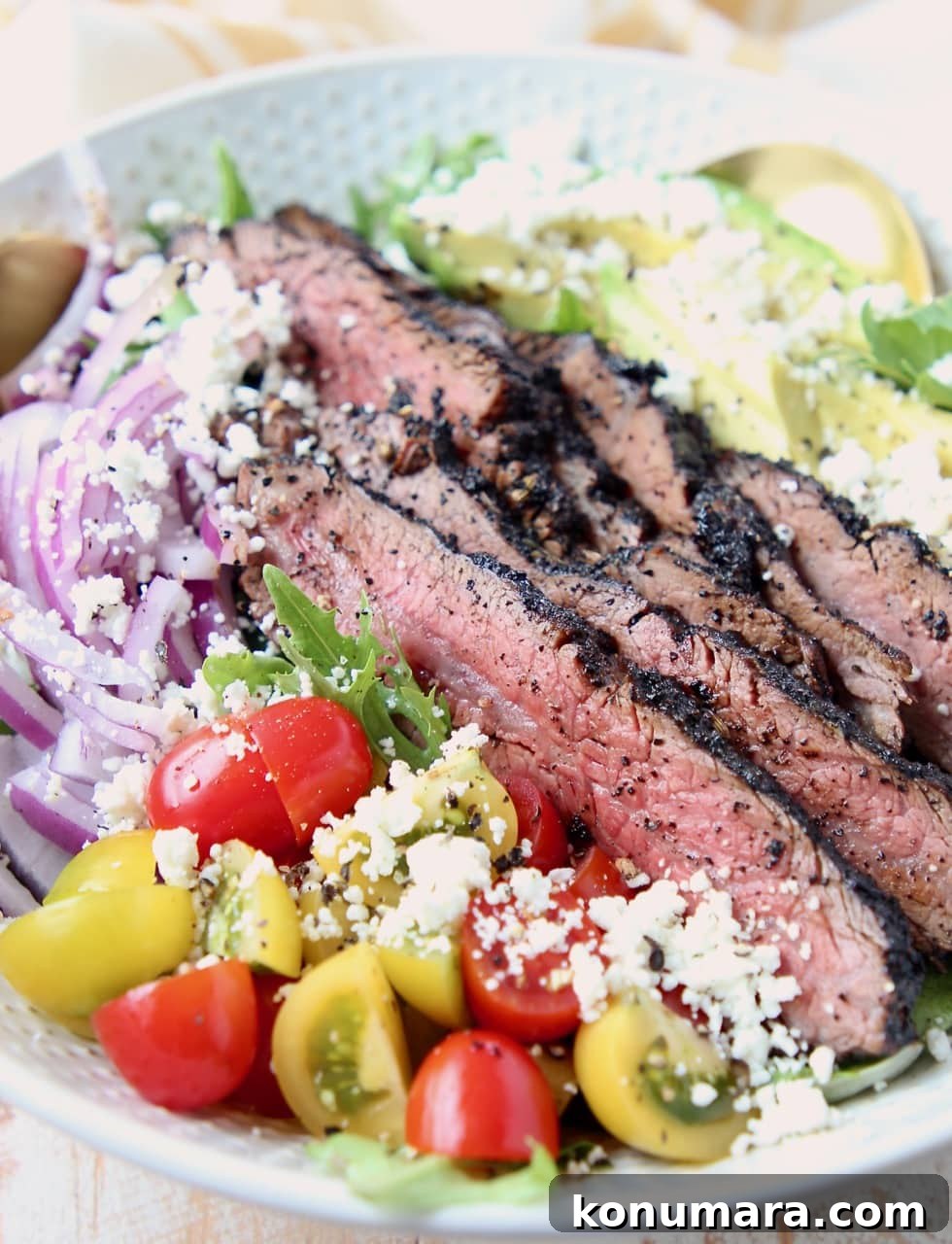 Sliced steak on a salad with cherry tomatoes, onions and goat cheese