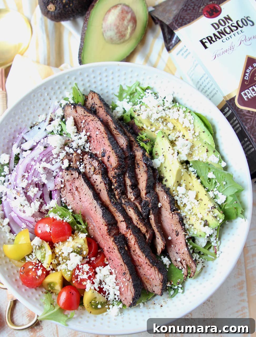 Steak salad in white bowl with bag of coffee and half an avocado on the side