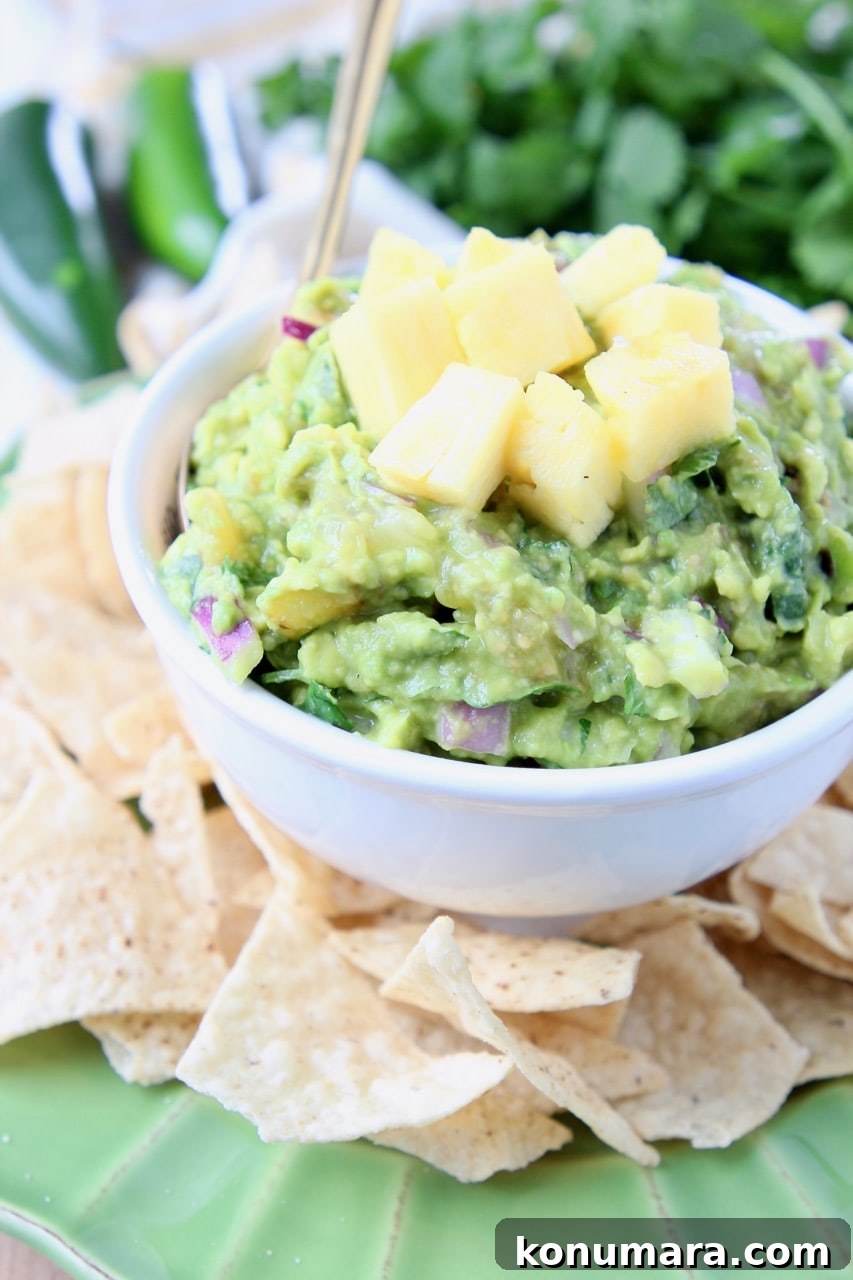 Pineapple guacamole in white bowl, surrounded by tortilla chips