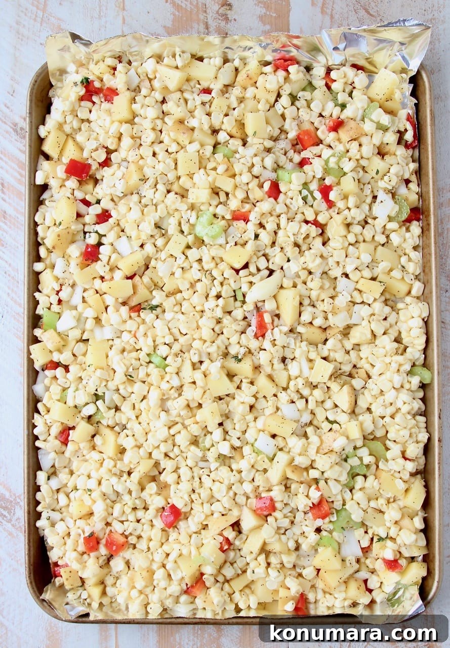 Corn, diced peppers and onions on foil lined baking sheet