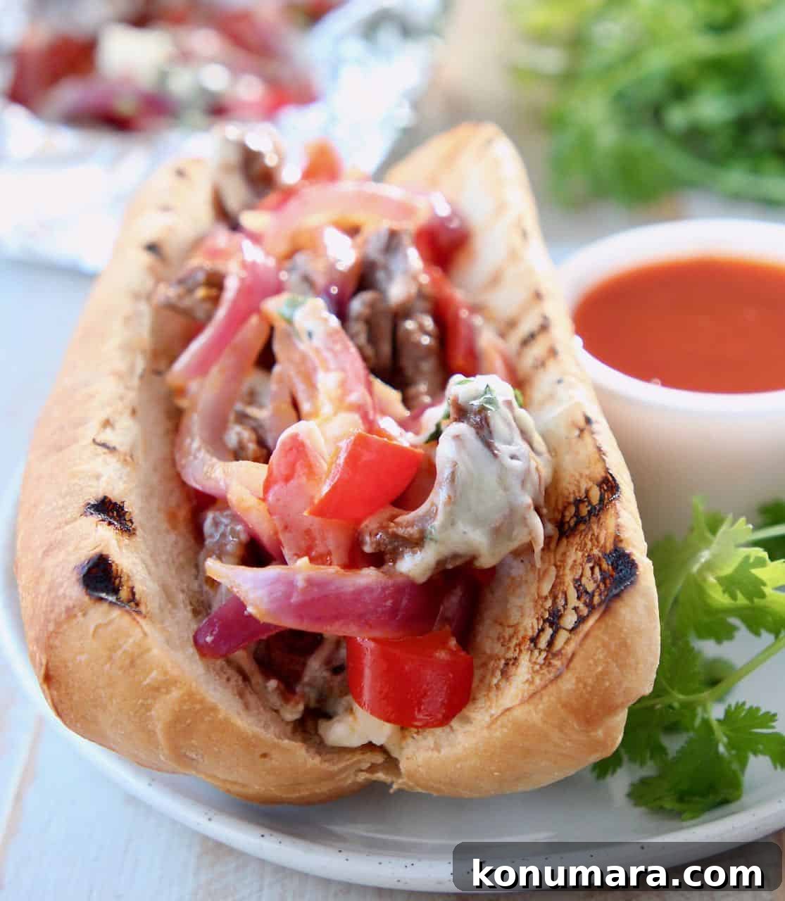 Philly cheesesteak sandwich on plate with buffalo sauce
