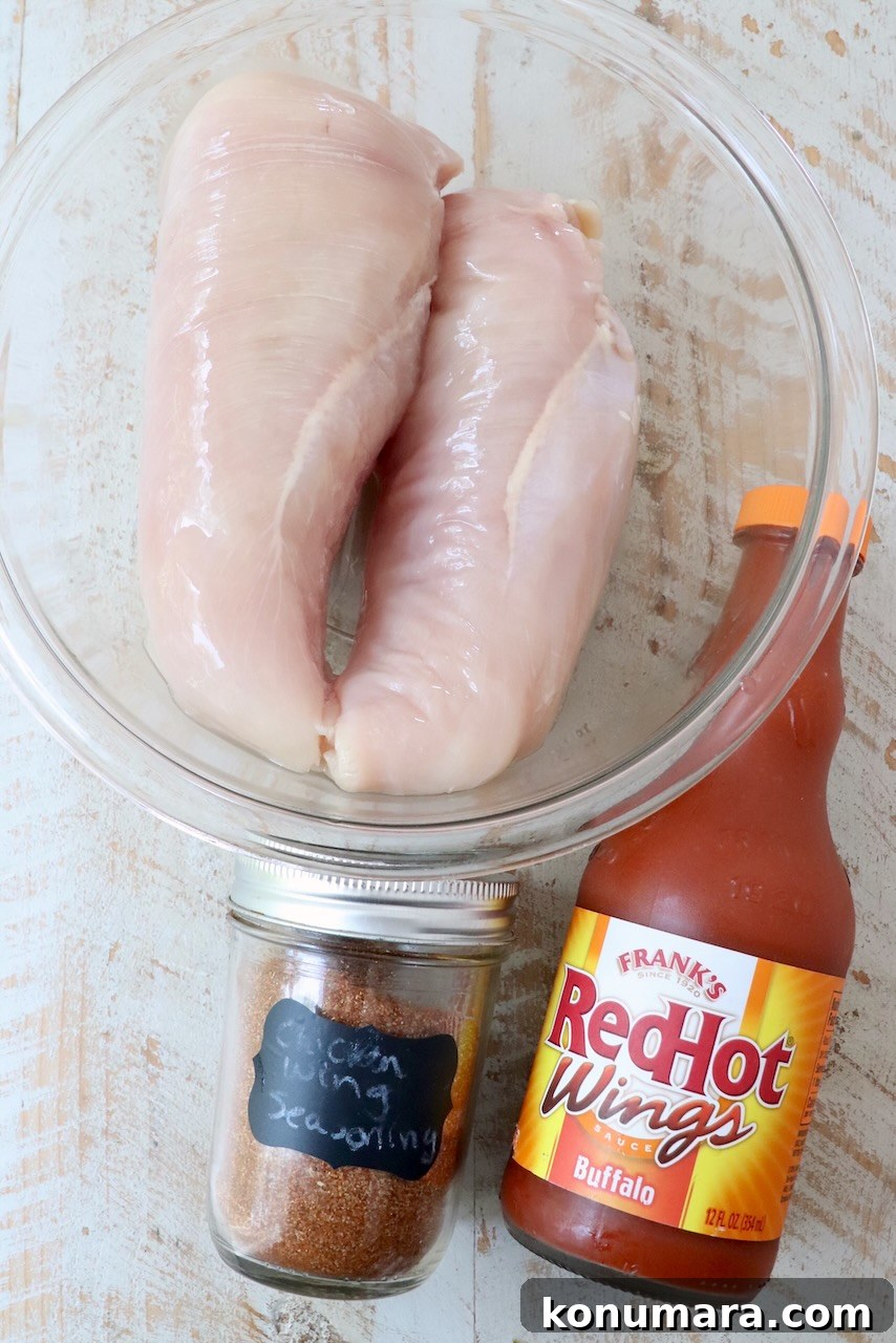 Slow Cooker Buffalo Chicken Recipe 3 ingredients for Instant Pot buffalo chicken on a white wood board
