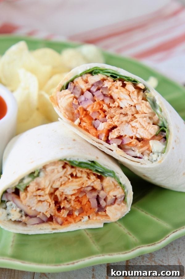 Slow Cooker Buffalo Chicken Recipe 5 Buffalo chicken wrap cut in half and leaning on each other on green plate with potato chips