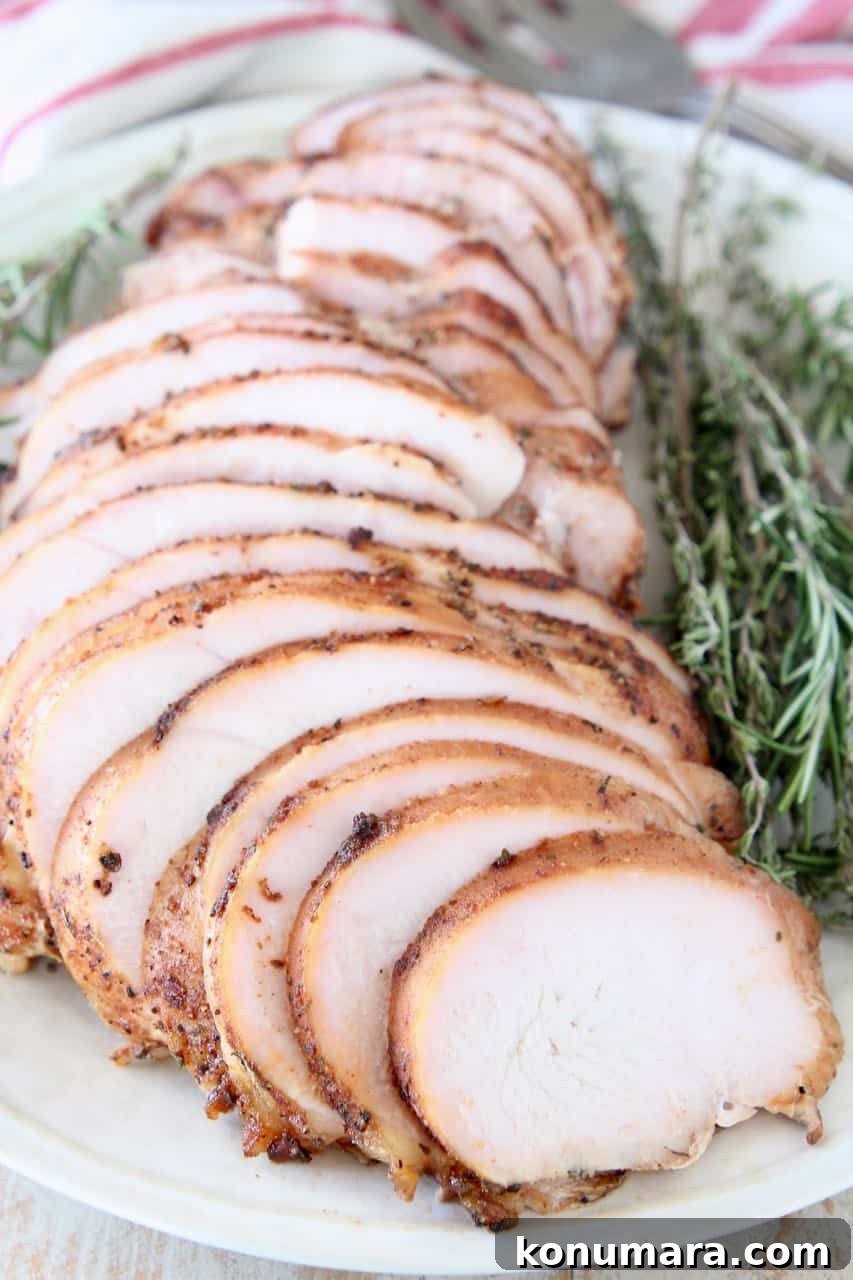 Sliced turkey breast on plate with fresh rosemary and thyme sprigs