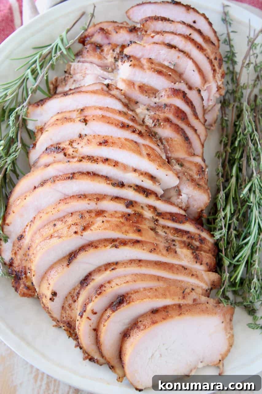 Sliced smoked turkey breast on plate with fresh herbs