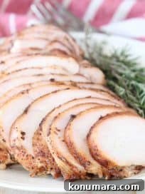 Sliced smoked turkey breast on plate with fresh rosemary and thyme