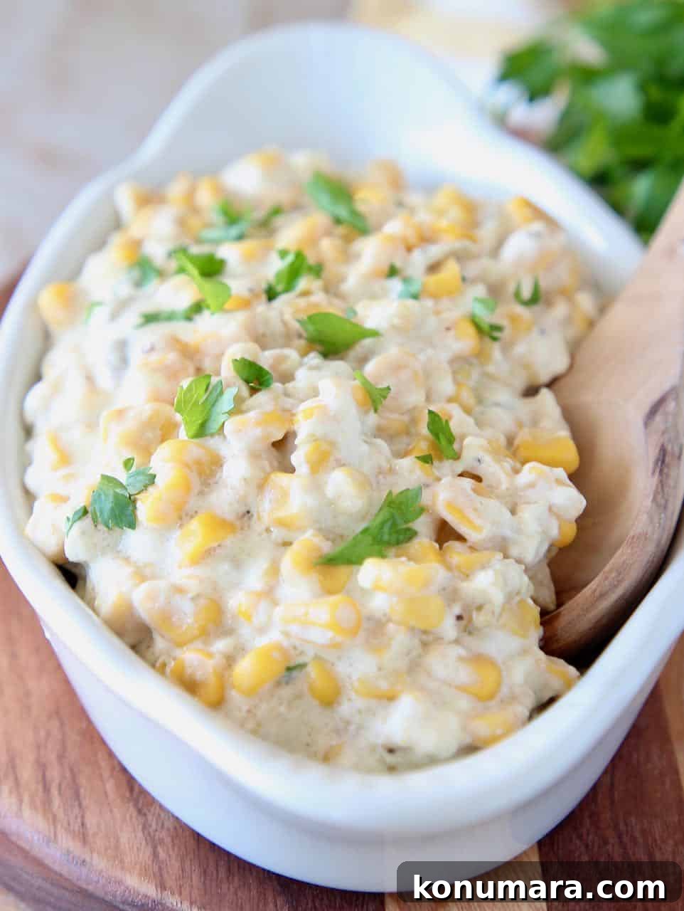 Creamed corn in serving dish with wooden spoon