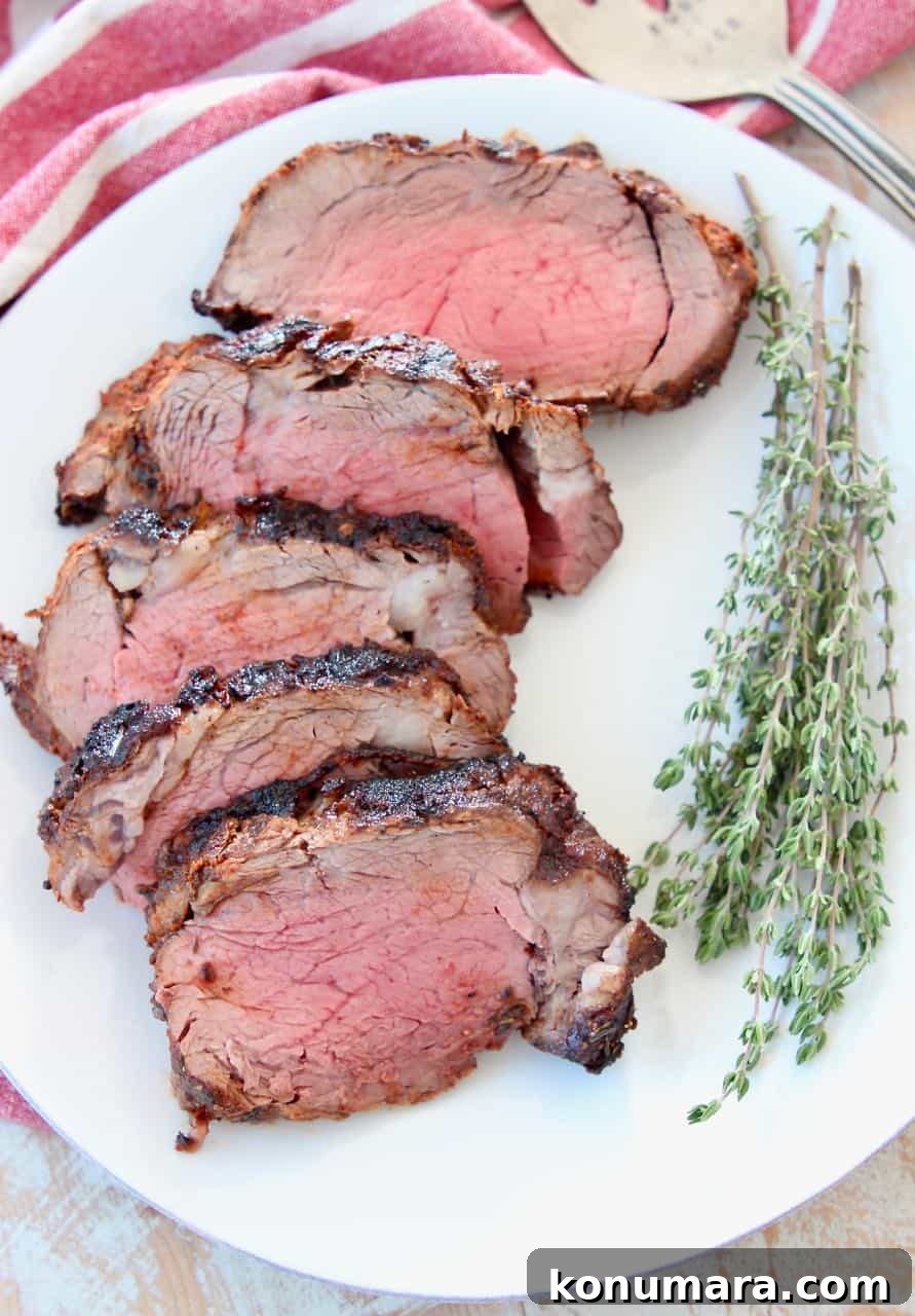 Slices of blackened beef tenderloin on white plate with fresh herbs