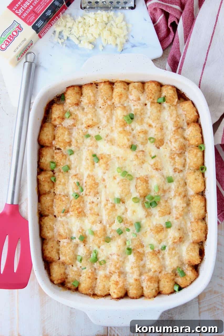 Breakfast tater tot casserole in casserole dish with red spatula on the side